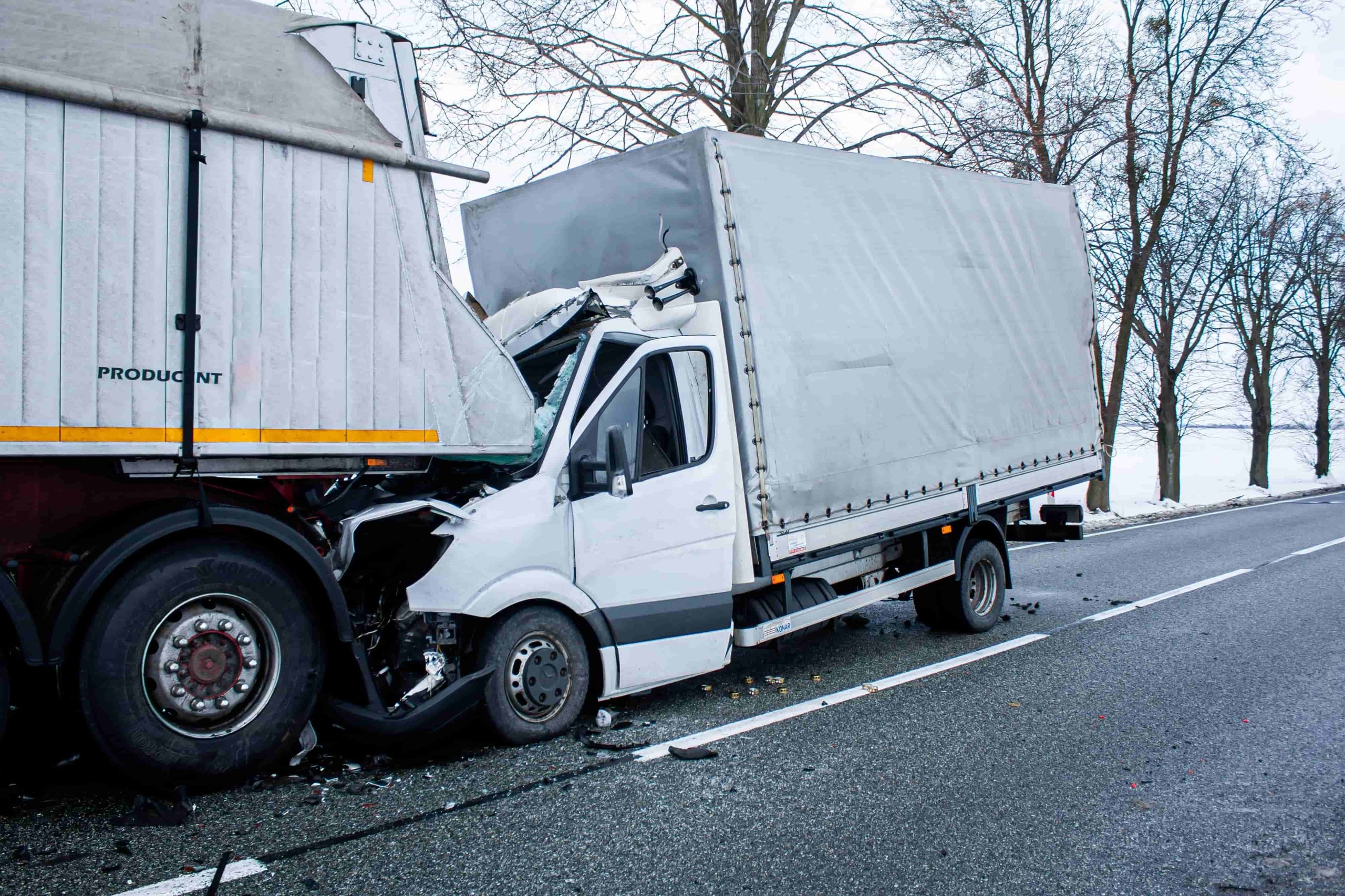 Serious truck accident with white delivery van crashed into rear of large semi-truck on highway.
