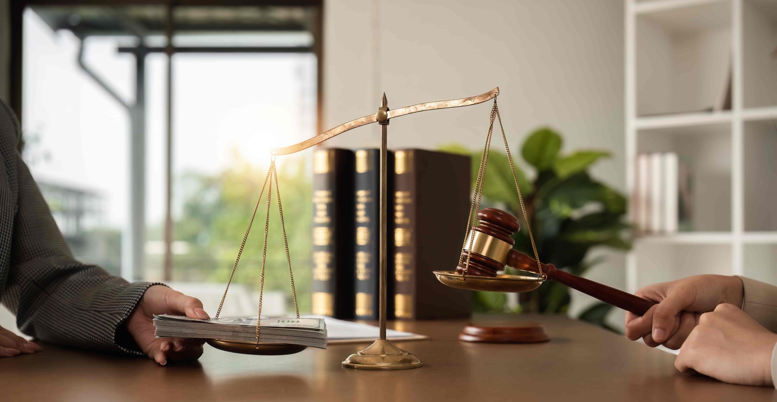 Scales of justice with gavel and money representing legal compensation and settlement negotiations